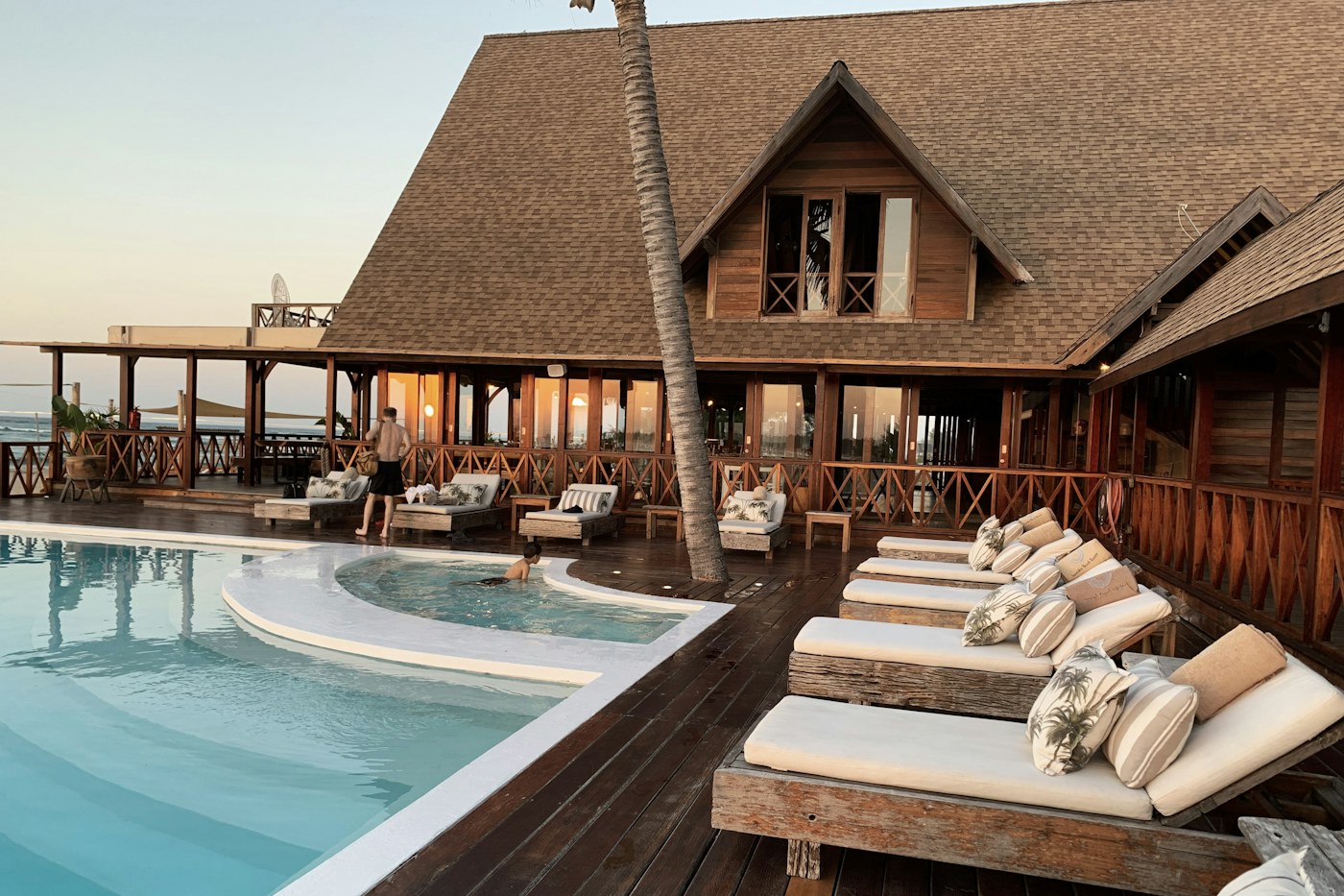 Beach resort pool framed by palms and pavilion architecture